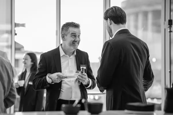 A guest chatting with an attendee in a monochrome event photograph at Goodwin — Management Incentives in the AI Era