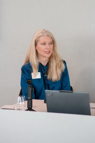 The panel moderator speaking beside a laptop at Goodwin — Management Incentives in the AI Era