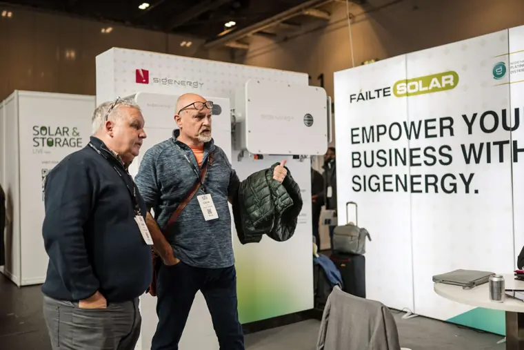 Two guests laughing beside the Fáilte Solar stand at Fáilte Solar at Solar & Storage