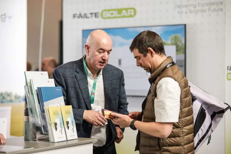 An exhibitor discussing product information with a visitor at Fáilte Solar at Solar & Storage