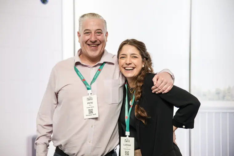 Two guests smiling together beside the stand at Fáilte Solar at Solar & Storage