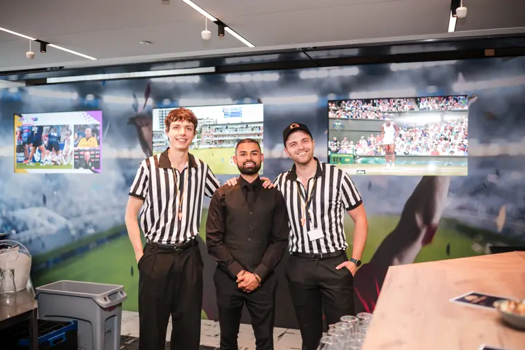 The event team together beside the sports screens at Goodwin Tavern.