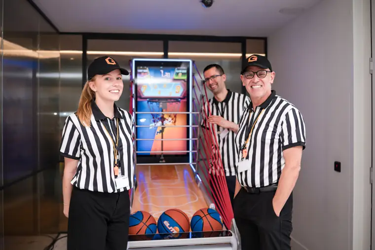 Bar staff posing beside the basketball game at Goodwin Tavern.