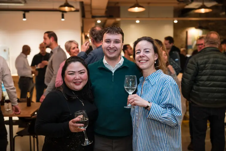Three guests smiling together at the reception.