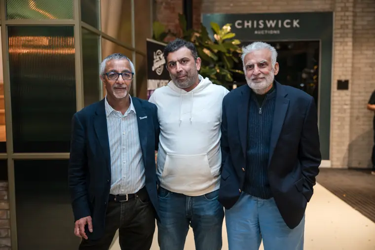 Three attendees posing outside the venue entrance.