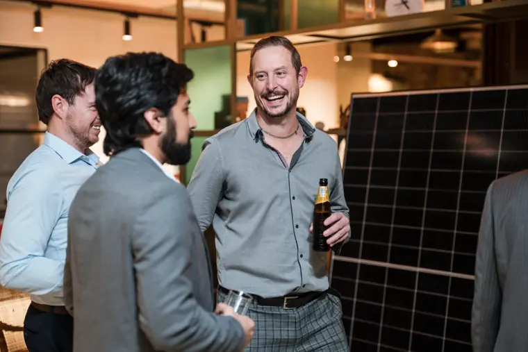 Business guests talking beside a solar panel display.