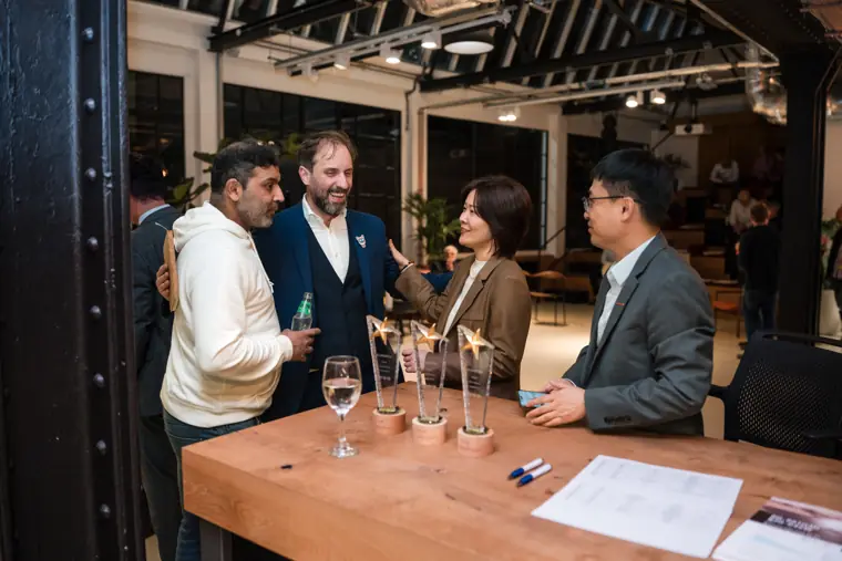 Guests sharing a drink beside the awards table.