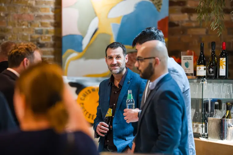 Attendees chatting beside the bar.