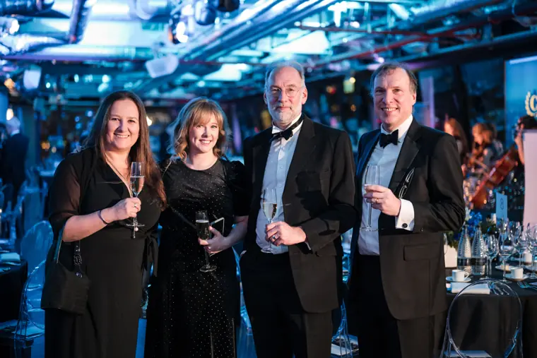 Four guests posing together over drinks.