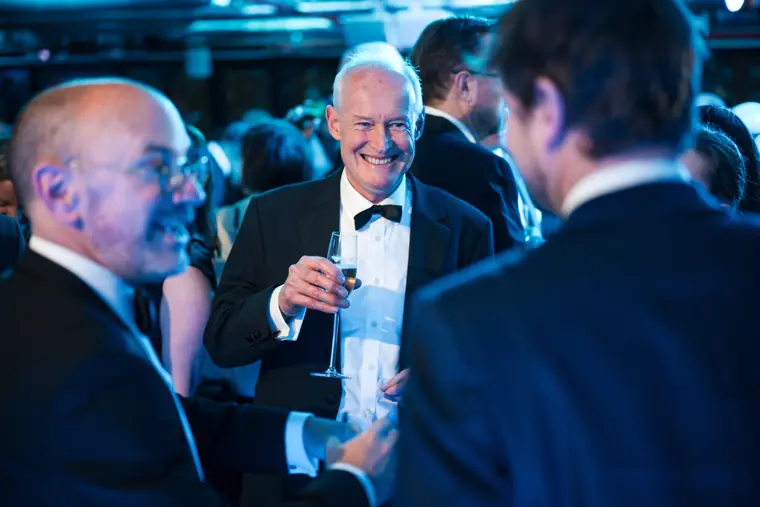 Guests greeting one another over a drink.