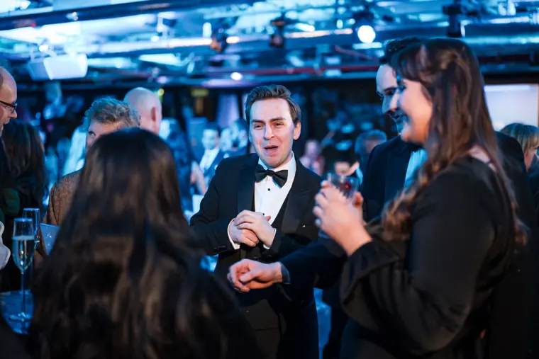 Guests chatting beneath the blue venue lights.
