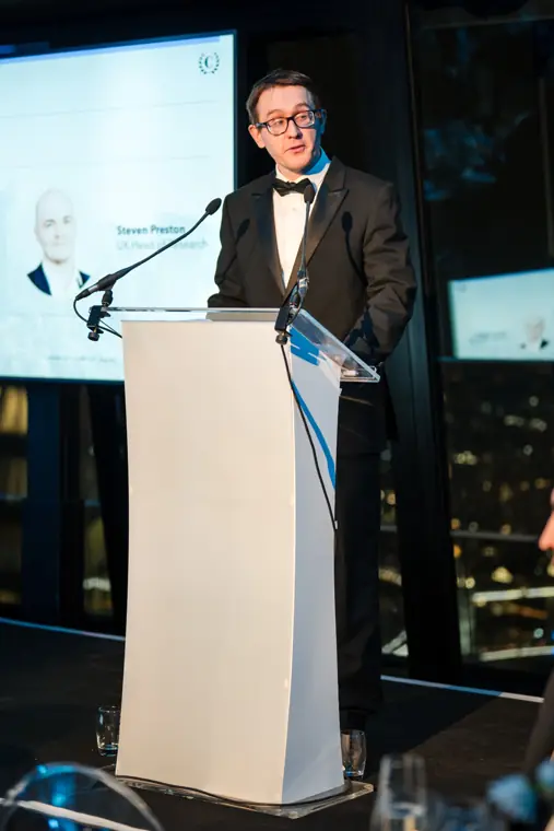 The presenter speaking beside the nominee screen.