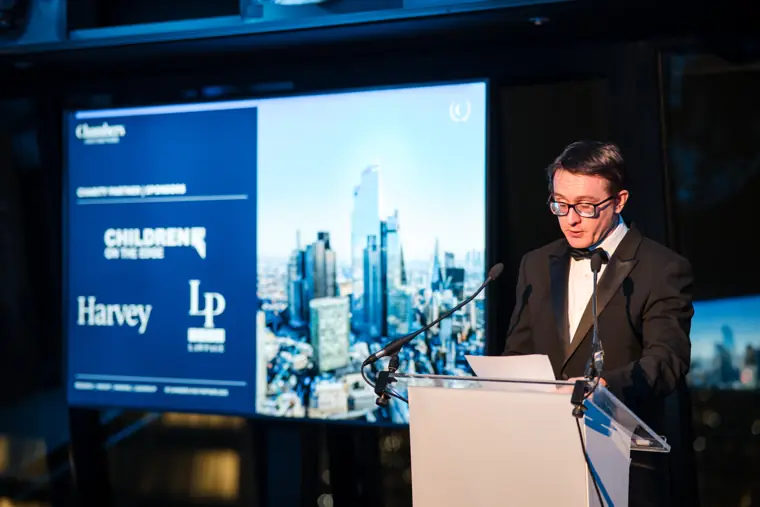The presenter speaking beneath the sponsor screens.