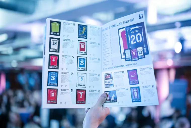 The printed auction catalogue in a guest's hands.