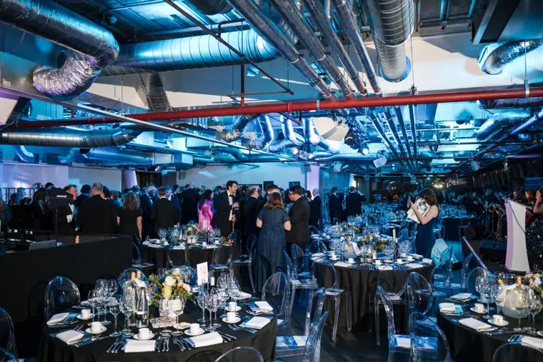 Guests filling the reception beside the dinner tables.