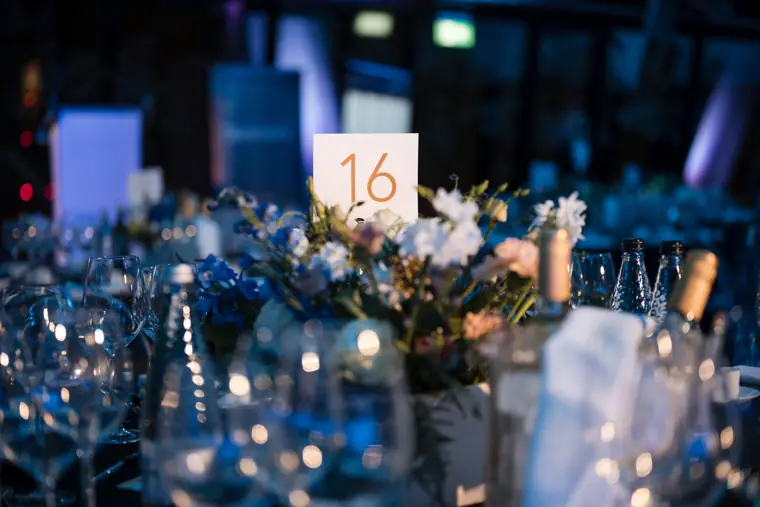 Flowers and tables beneath the ceremony lighting.