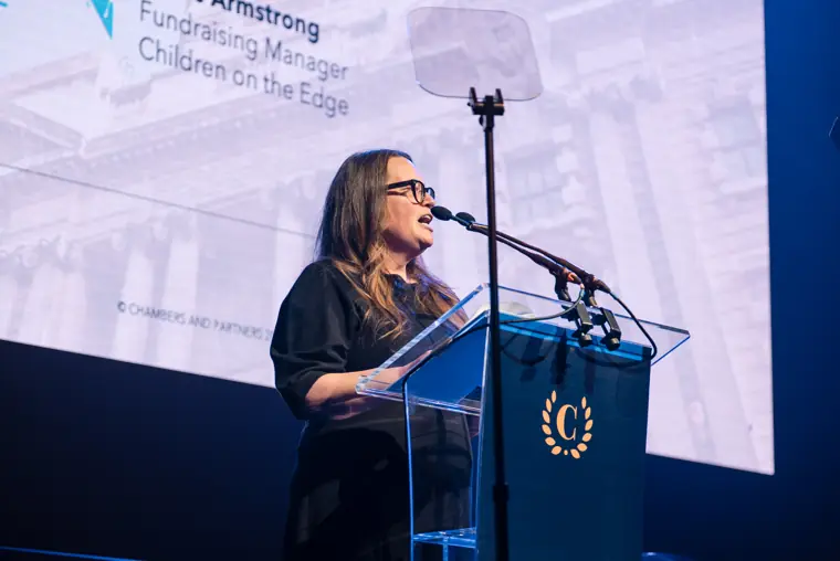 A presenter speaking with the nominee screen behind her.