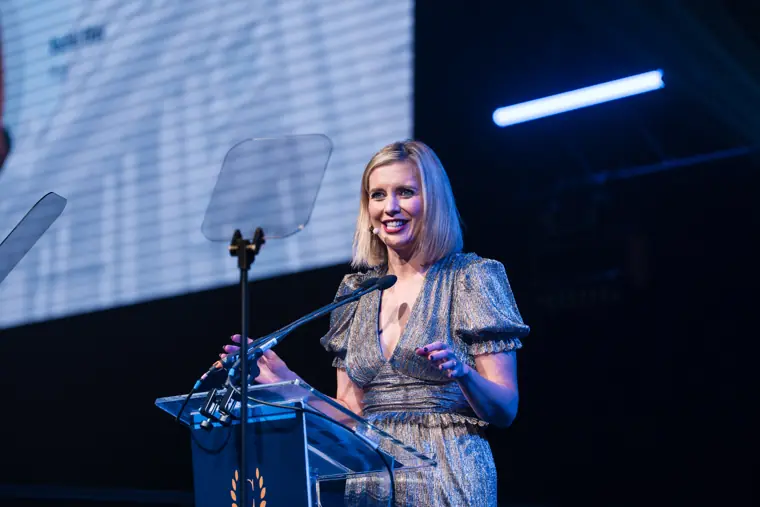 A presenter smiling at the lectern.
