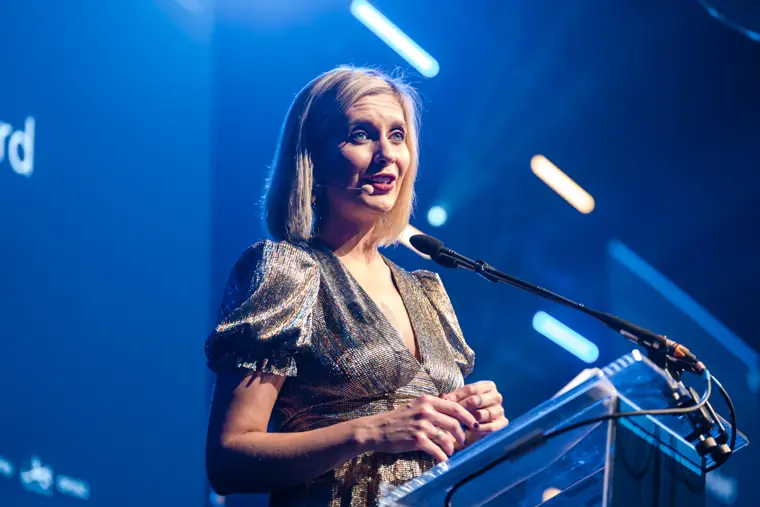 An award presenter on the lit stage.