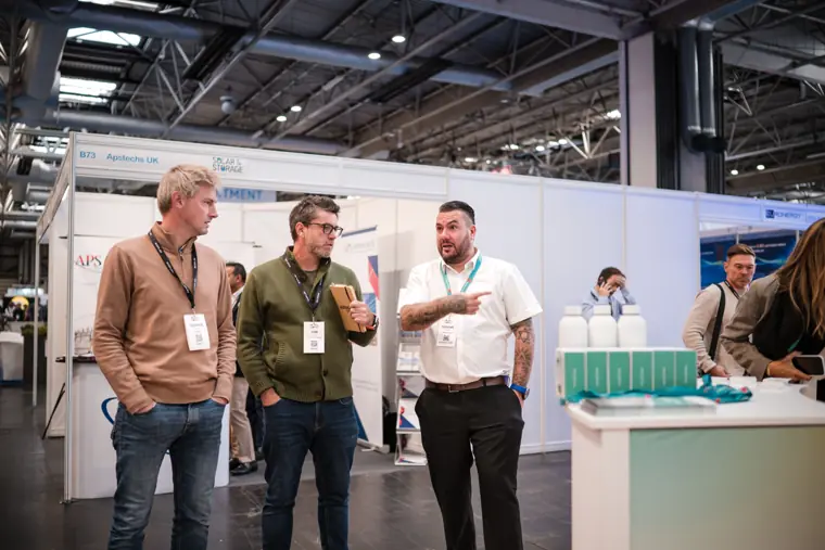 Three visitors talking beside the product display.