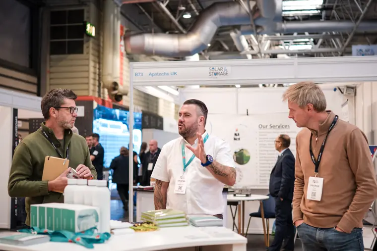 A team member talking with two trade show visitors.