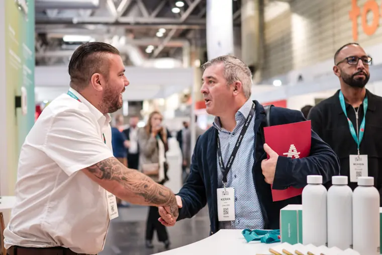 Two attendees greeting each other at the exhibition.