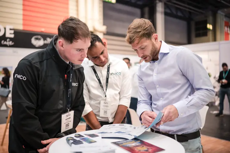 Visitors looking over a printed product sheet.