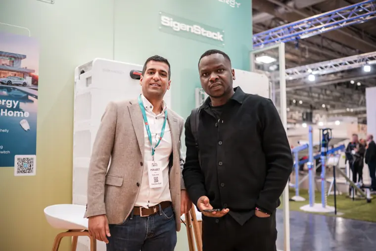 Two attendees photographed beside the branded display.