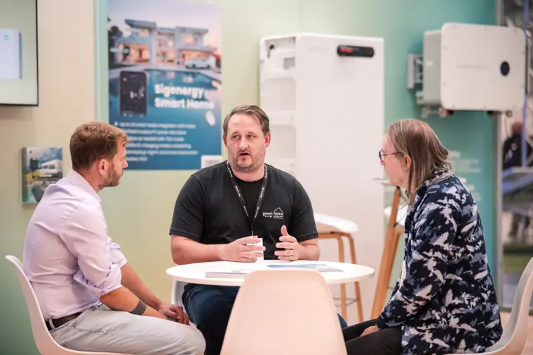 Three attendees talking around a small table.