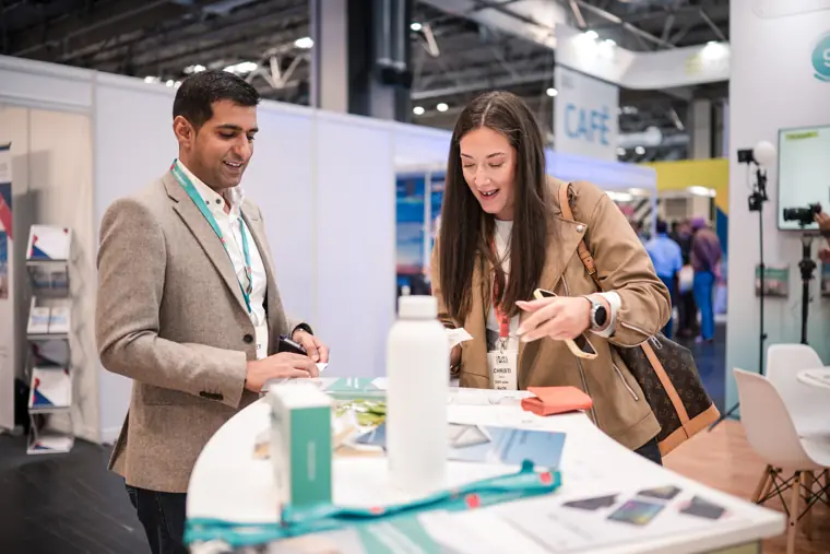 Two attendees reviewing material on the stand.
