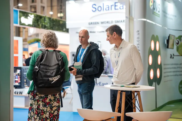 Three people discuss the display at the stand.