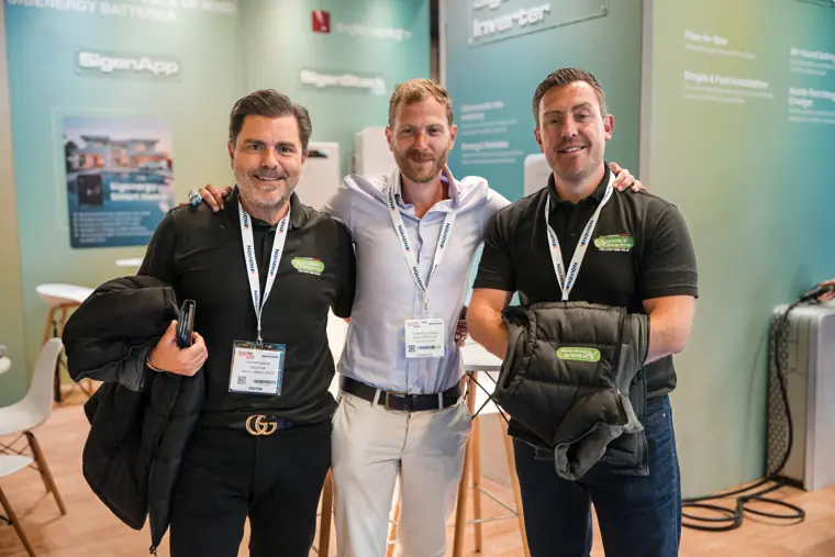 Three members of the team pose beside the stand.
