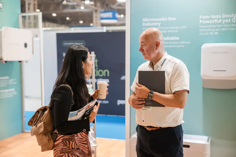 A team member speaks with a visitor by the battery display.