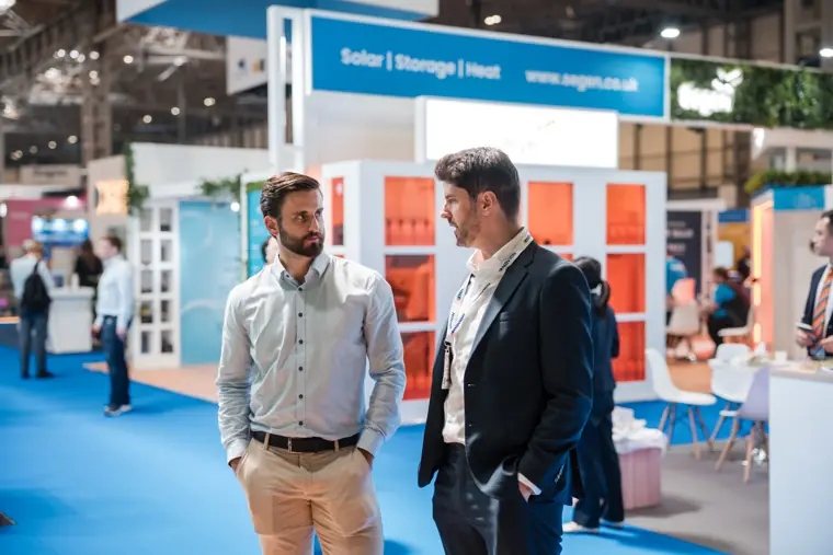 Attendees talk in the exhibition aisle.