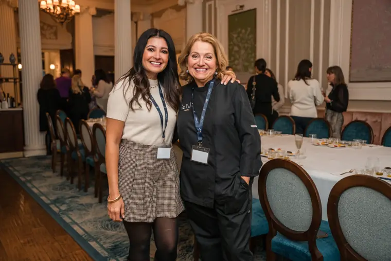 Two attendees posing together beside the table.