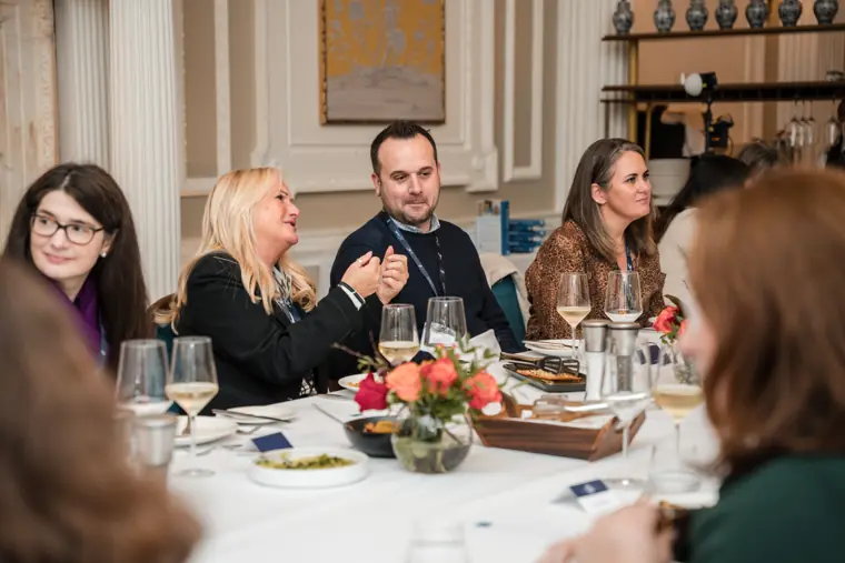 Guests listening across the dinner table.