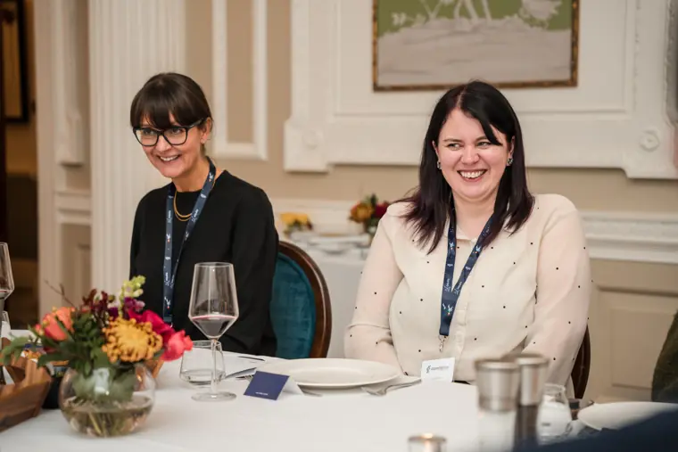 Guests smiling around the dinner table.