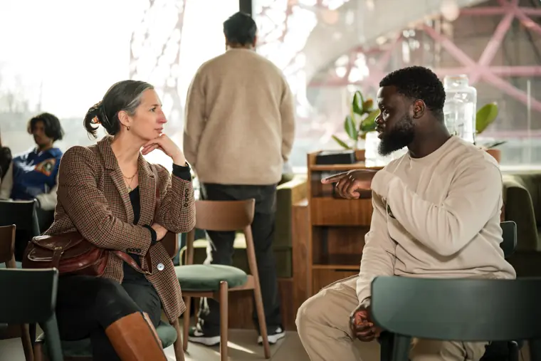 A founder and mentor talk near the windows.