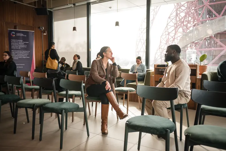 Two attendees hold a conversation by the seating.