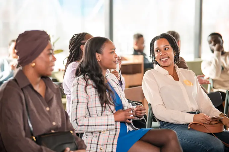 Three participants share a conversation near the seating.