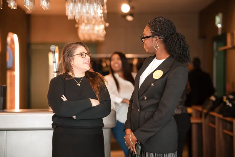 Two attendees talk in the reception area.