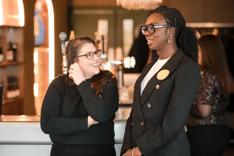Two guests continue a conversation at the bar.