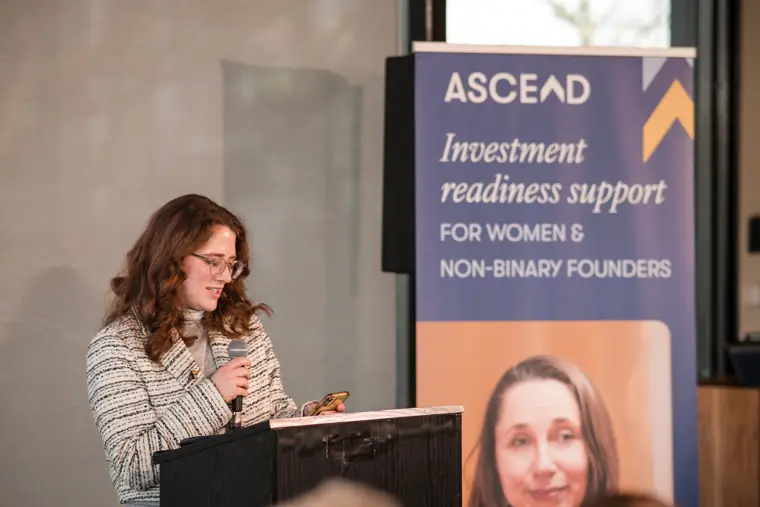 A programme host speaks at the lectern.