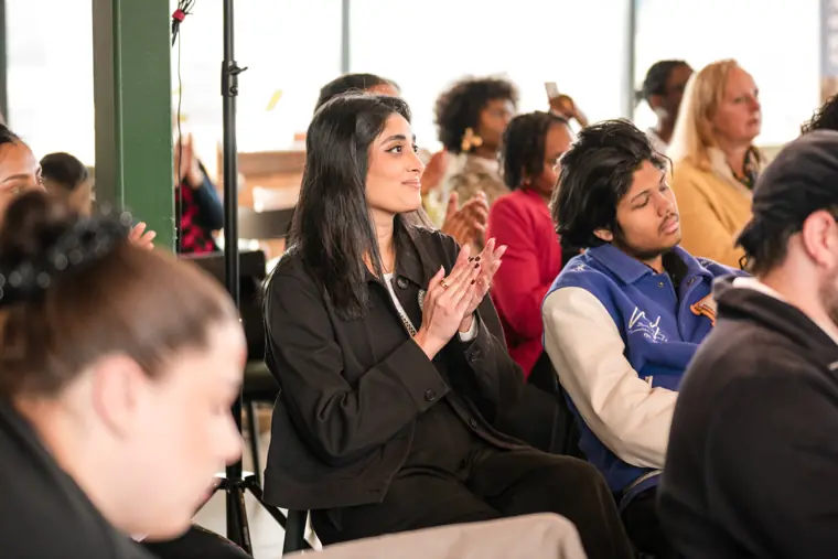 Audience members applaud a founder pitch.