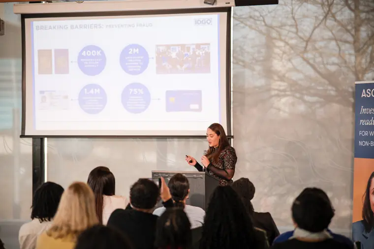 A wide view of a founder presenting to the seated audience.