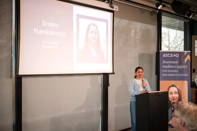 A founder presents from the lectern beside the Ascend sign.