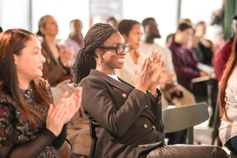 An attendee applauds in the front row.