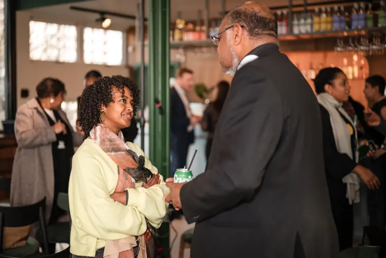 A guest speaks with another attendee at the bar.