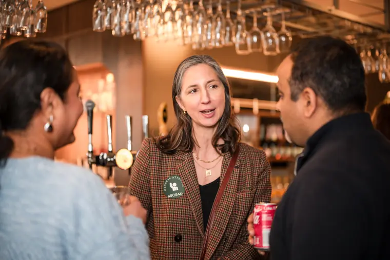 Three guests continue a conversation by the refreshments.