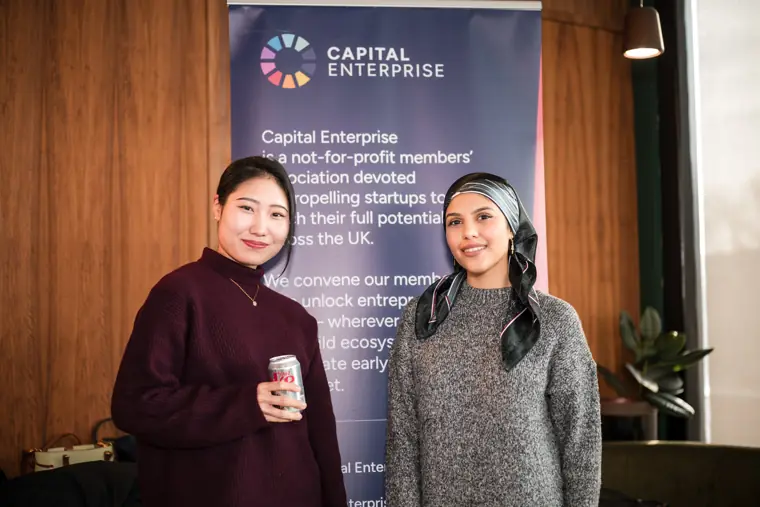Two participants stand beside the Capital Enterprise banner.